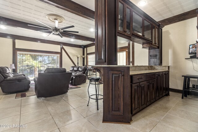 1412 US Highway 167, Abbeville, LA 70510 - kitchen with open floor plan, a ceiling fan, a breakfast bar area, dark brown cabinets, and glass insert cabinets