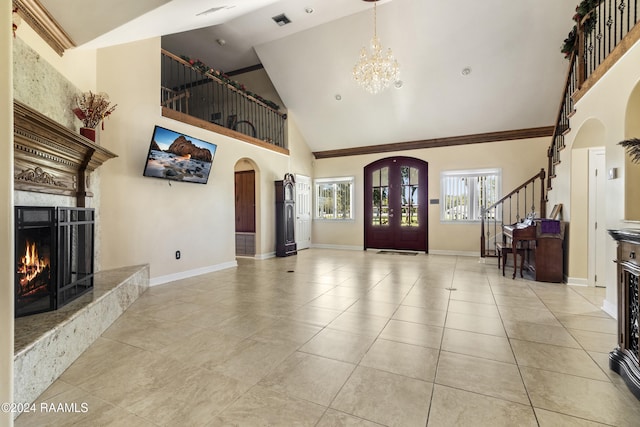 entrance foyer featuring french doors, a fireplace, light tile patterned floors, high vaulted ceiling, and a chandelier