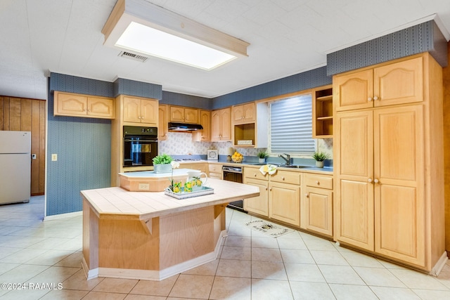 kitchen with black oven, tile counters, light tile patterned flooring, and white refrigerator