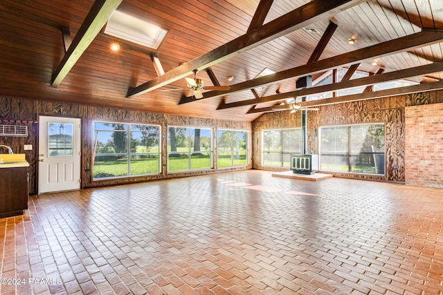 unfurnished sunroom with a wood stove, ceiling fan, vaulted ceiling with skylight, and wood ceiling