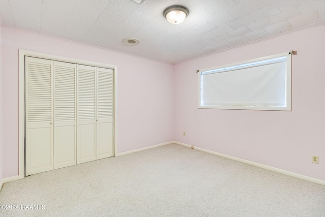 unfurnished bedroom with light carpet and a closet