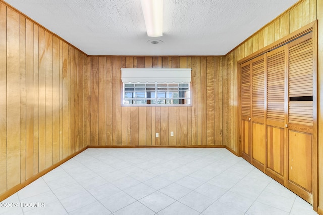 spare room featuring a textured ceiling and wooden walls