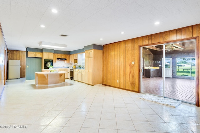 kitchen featuring backsplash, wooden walls, oven, white fridge, and a kitchen island