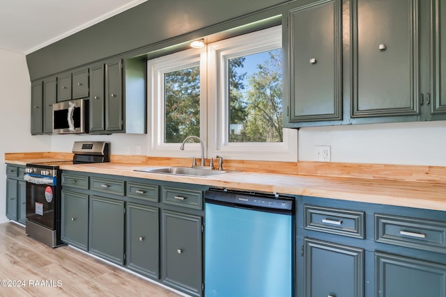 kitchen featuring butcher block countertops, light hardwood / wood-style flooring, stainless steel appliances, and sink