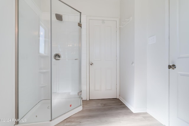 bathroom featuring hardwood / wood-style flooring and a shower with shower door