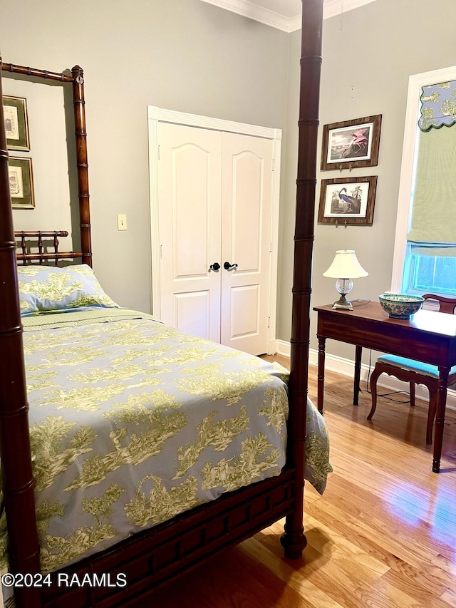 bedroom with light wood-type flooring, ornamental molding, and a closet