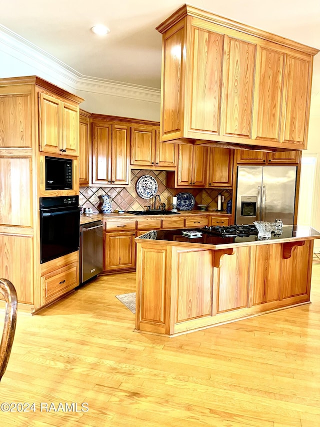 kitchen with a kitchen breakfast bar, ornamental molding, black appliances, and light hardwood / wood-style floors