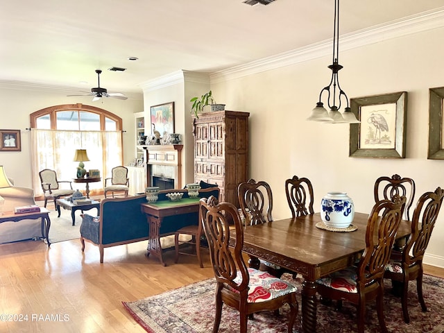 dining space with hardwood / wood-style floors, ceiling fan with notable chandelier, and ornamental molding