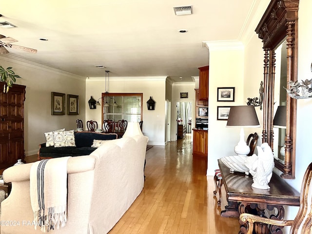 living room with light hardwood / wood-style flooring, ceiling fan, and crown molding