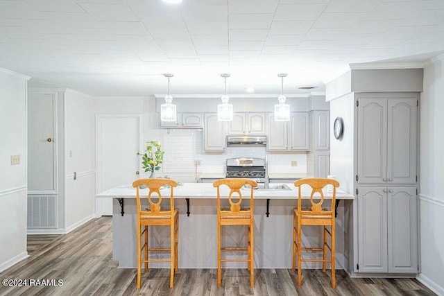 kitchen with a kitchen breakfast bar, tasteful backsplash, dark hardwood / wood-style flooring, stainless steel range oven, and a center island with sink