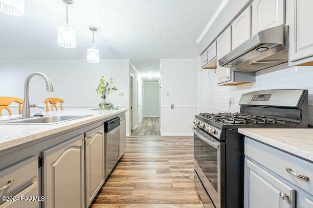 kitchen featuring gray cabinetry, sink, decorative light fixtures, appliances with stainless steel finishes, and light wood-type flooring