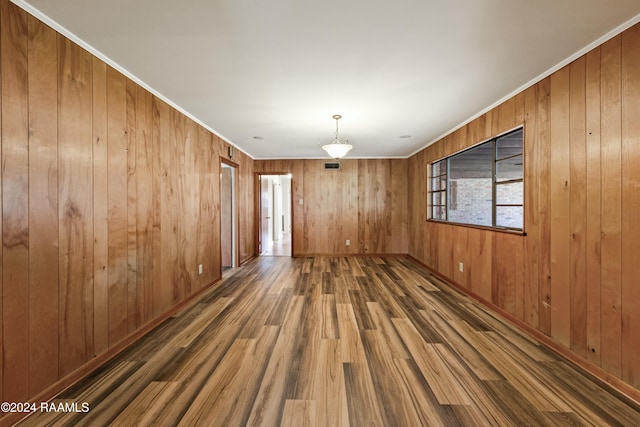 spare room with ornamental molding, dark hardwood / wood-style flooring, and wooden walls