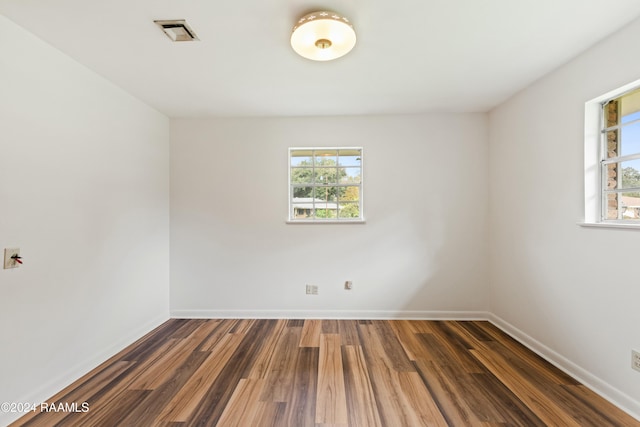 empty room with plenty of natural light and dark wood-type flooring