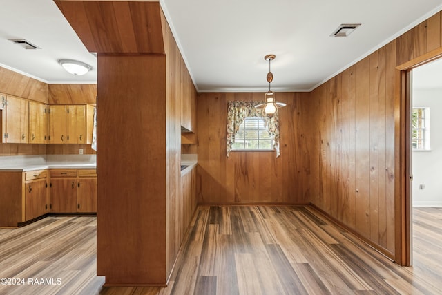 unfurnished dining area with hardwood / wood-style floors, ornamental molding, and wooden walls