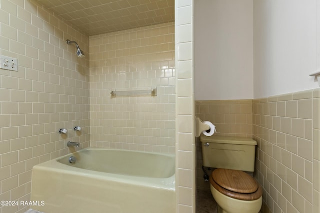 bathroom featuring tiled shower / bath combo, tile walls, and toilet