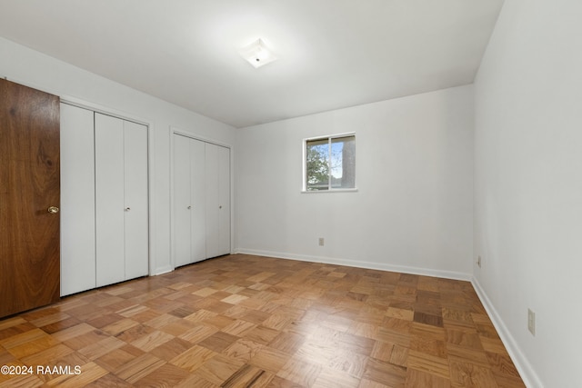 unfurnished bedroom with light parquet floors and two closets