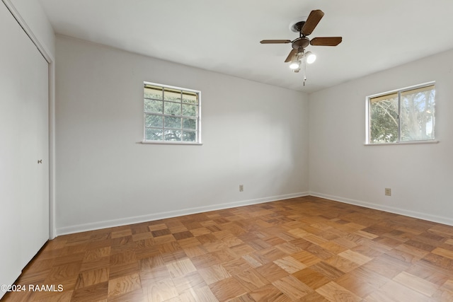 empty room with ceiling fan, light parquet floors, and a healthy amount of sunlight