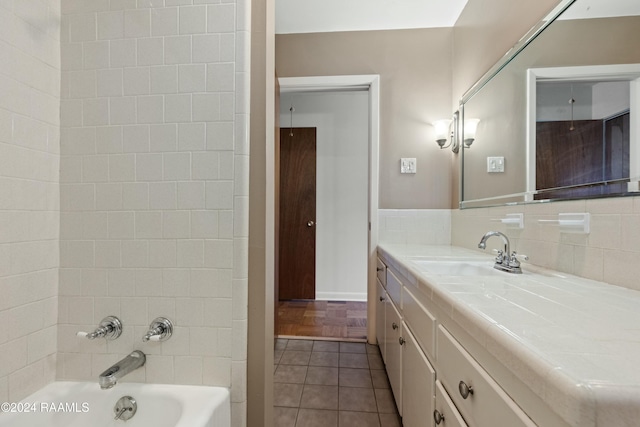 bathroom with tile patterned floors, tasteful backsplash, vanity, and tiled shower / bath