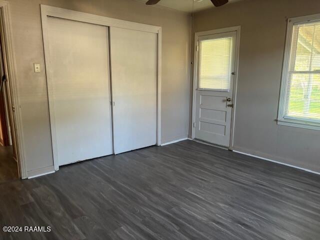 unfurnished bedroom with dark hardwood / wood-style flooring, a closet, and ceiling fan