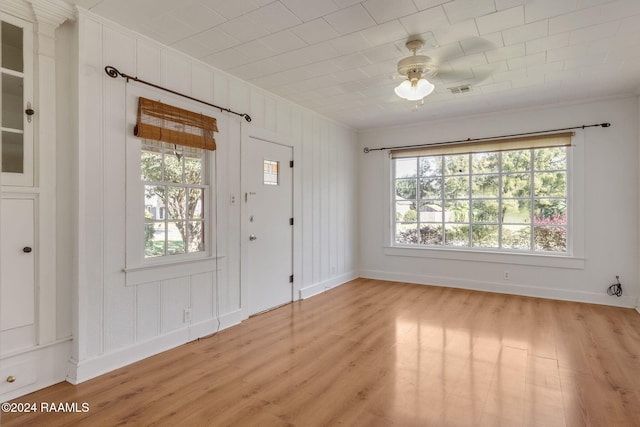 foyer with light wood-type flooring, crown molding, and a wealth of natural light