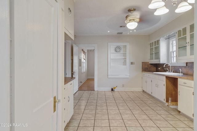 kitchen with light tile patterned floors, tasteful backsplash, white cabinetry, and sink