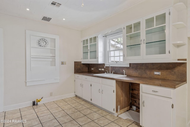 kitchen featuring light tile patterned floors, tasteful backsplash, white cabinetry, and sink