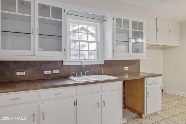 kitchen with white cabinets, decorative backsplash, light tile patterned floors, and sink