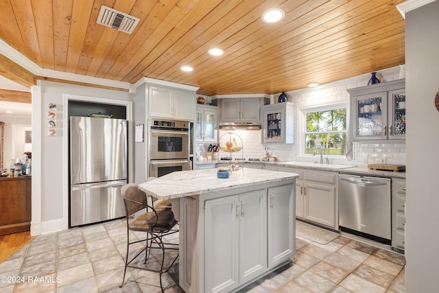 kitchen with a kitchen island, light stone counters, wood ceiling, and stainless steel appliances