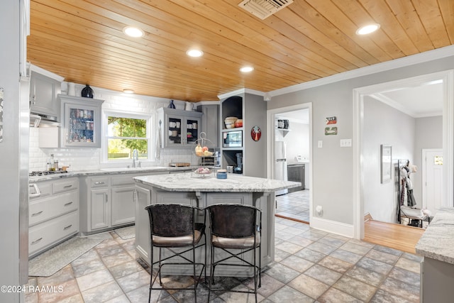 kitchen featuring a kitchen island, light stone countertops, wood ceiling, and tasteful backsplash