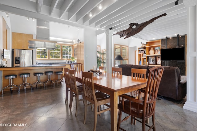 dining space with beamed ceiling and decorative columns