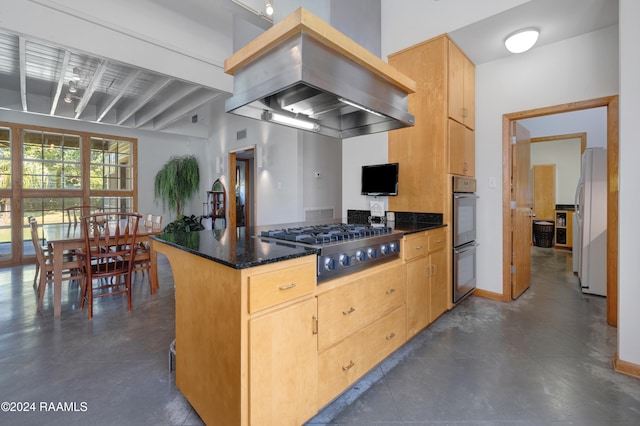 kitchen with beam ceiling, stainless steel appliances, dark stone counters, island range hood, and light brown cabinetry