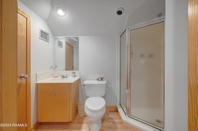 bathroom featuring walk in shower, hardwood / wood-style floors, vaulted ceiling, toilet, and vanity