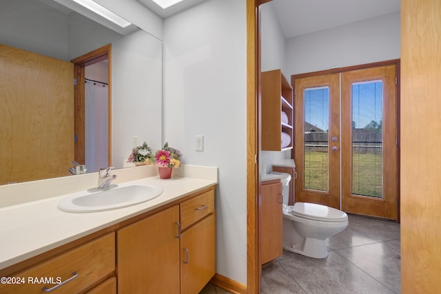 bathroom featuring tile patterned floors, french doors, vanity, and toilet