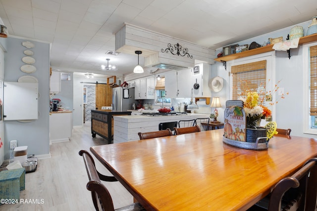 dining space featuring a barn door, light wood-type flooring, and crown molding