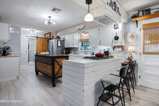 kitchen featuring white cabinets, a barn door, light wood-type flooring, appliances with stainless steel finishes, and kitchen peninsula