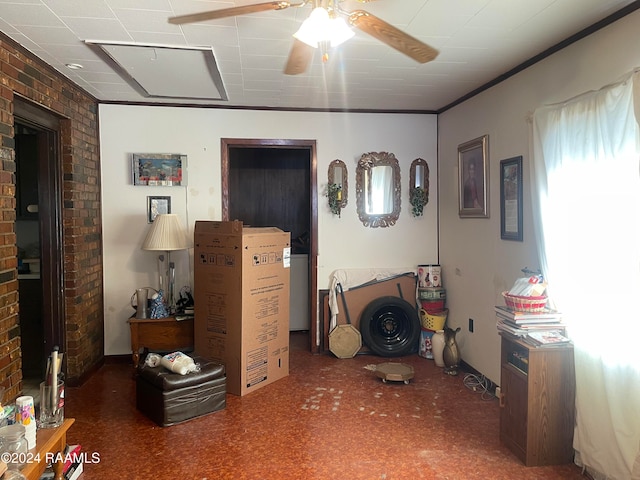 living room featuring ceiling fan, crown molding, and brick wall