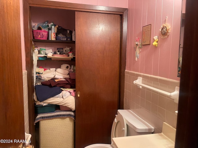 bathroom featuring tile walls and toilet