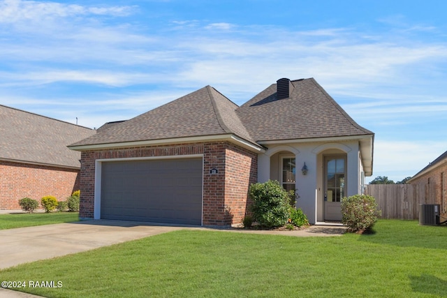 view of front of home with cooling unit, a garage, and a front yard