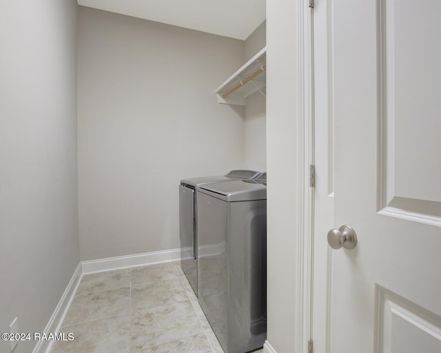 laundry area with washer and clothes dryer and light tile patterned floors