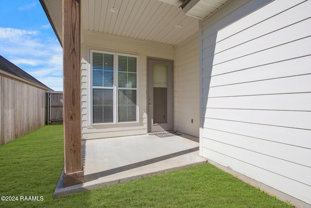 property entrance with a lawn and a patio area