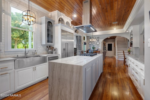 kitchen with a wealth of natural light, stainless steel appliances, island range hood, white cabinets, and wood ceiling