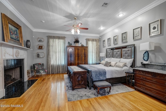 bedroom with ceiling fan, a premium fireplace, crown molding, and light hardwood / wood-style flooring