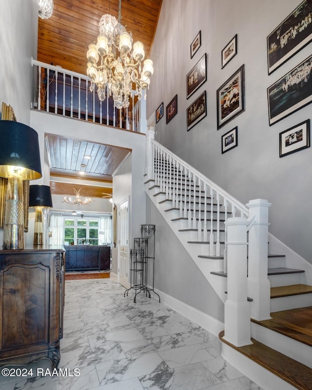 stairway with wooden ceiling, a high ceiling, and a notable chandelier