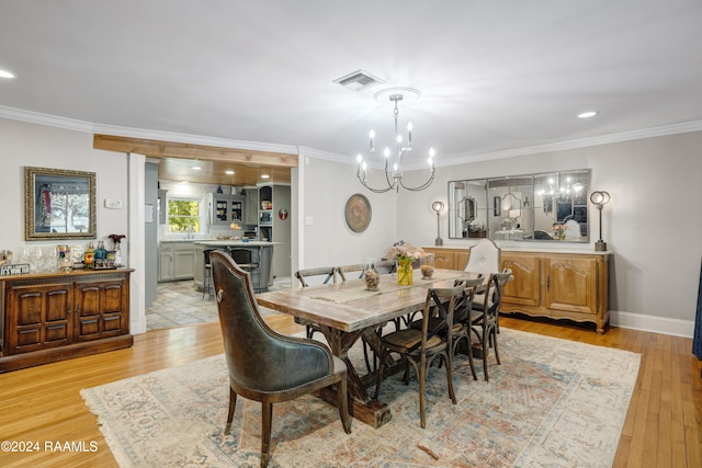 dining room with an inviting chandelier, ornamental molding, and light hardwood / wood-style flooring