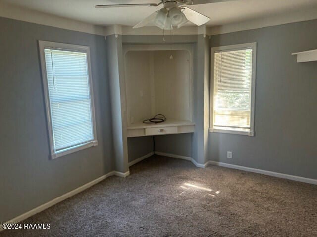 unfurnished bedroom featuring ceiling fan, carpet floors, and built in desk