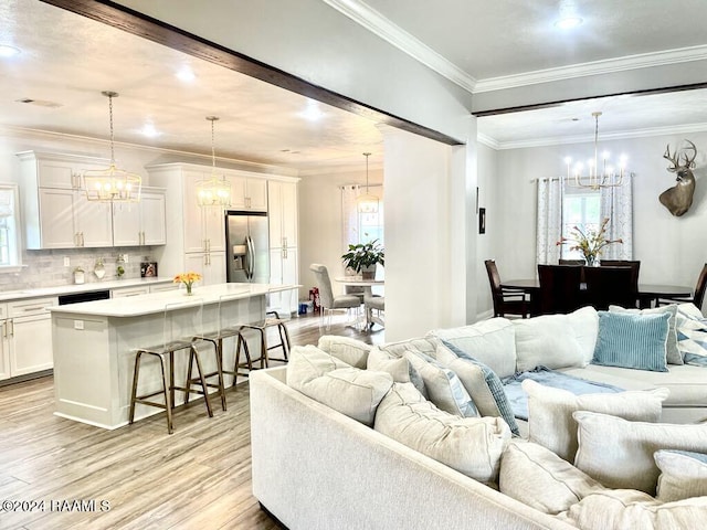 living room with light wood-type flooring, plenty of natural light, and ornamental molding