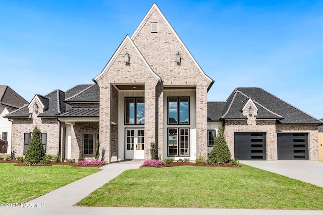 french country inspired facade featuring a standing seam roof, brick siding, a front lawn, and metal roof