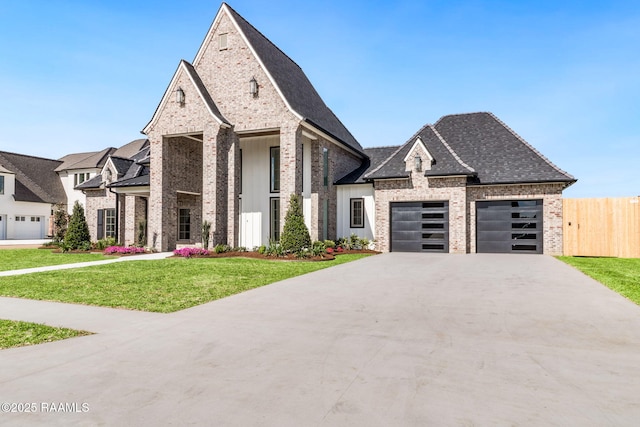 french country inspired facade with concrete driveway, an attached garage, a front lawn, brick siding, and fence