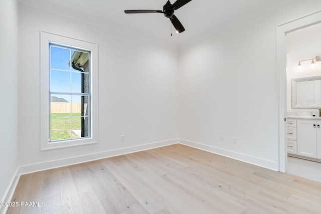 spare room featuring light wood-style floors, baseboards, and a ceiling fan