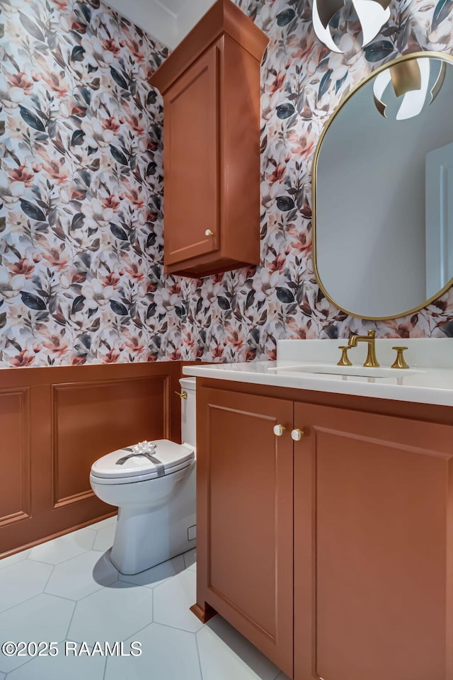 half bath featuring toilet, tile patterned floors, wallpapered walls, and vanity